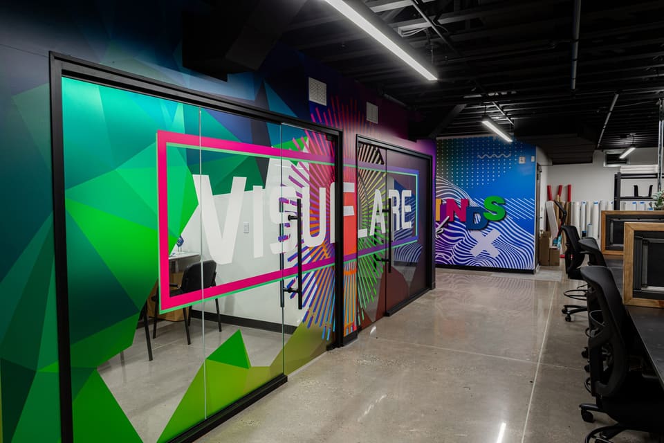Glass-fronted studio rooms with large white lettering and green geometric wall print