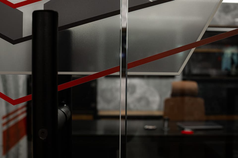 Close view of angled frost and a red stripe on a glass door beside a black door handle