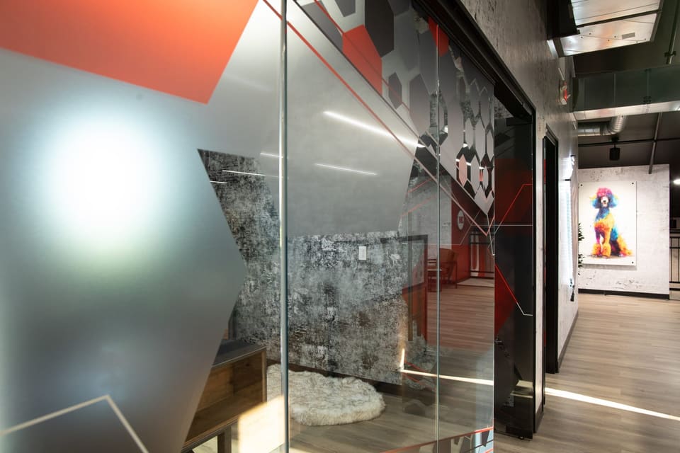 Glass wall with a large frosted shape and red graphic, looking down a corridor with a framed artwork