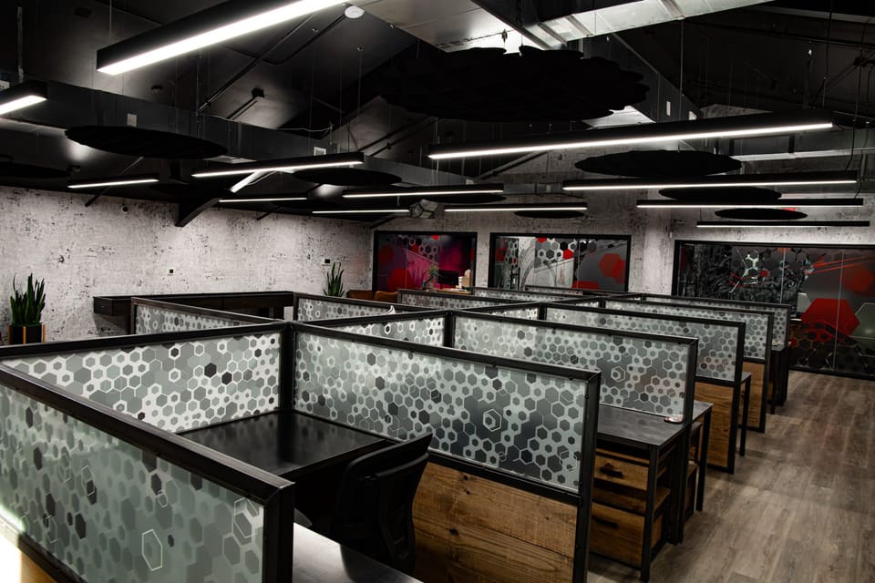 Rows of workstations with hexagon-pattern panels and patterned glass offices behind