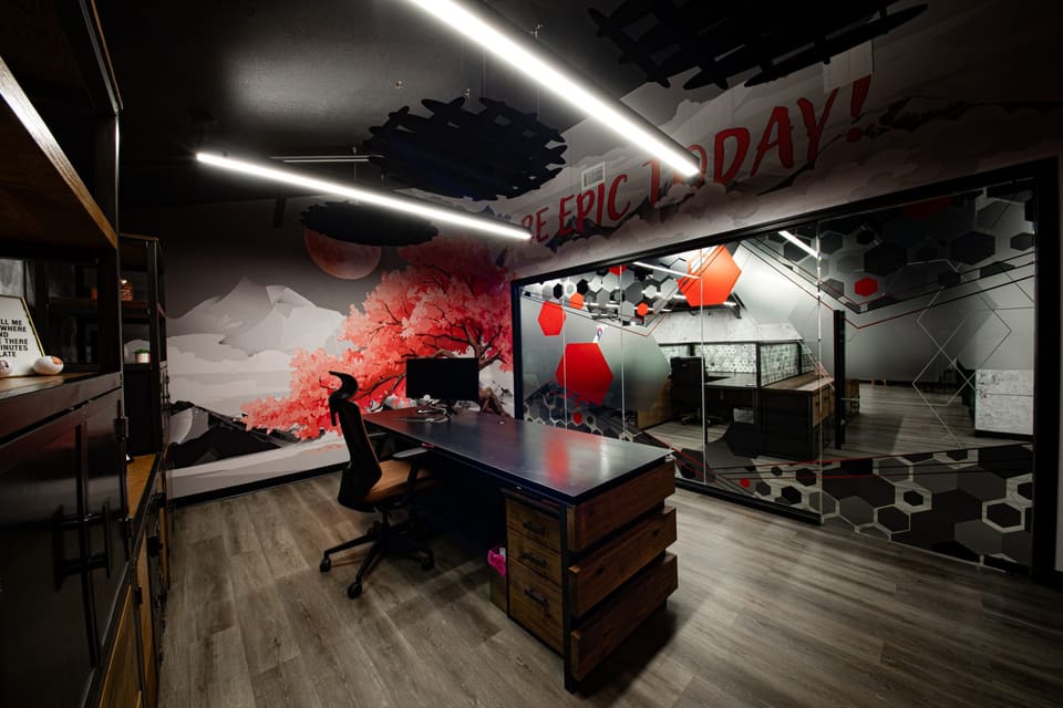 Private office with a landscape mural of a red tree and mountains behind a desk