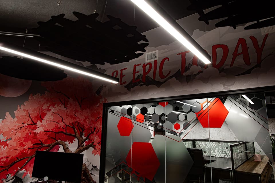 Mural lettering overhead and a hexagon-patterned glass office behind it