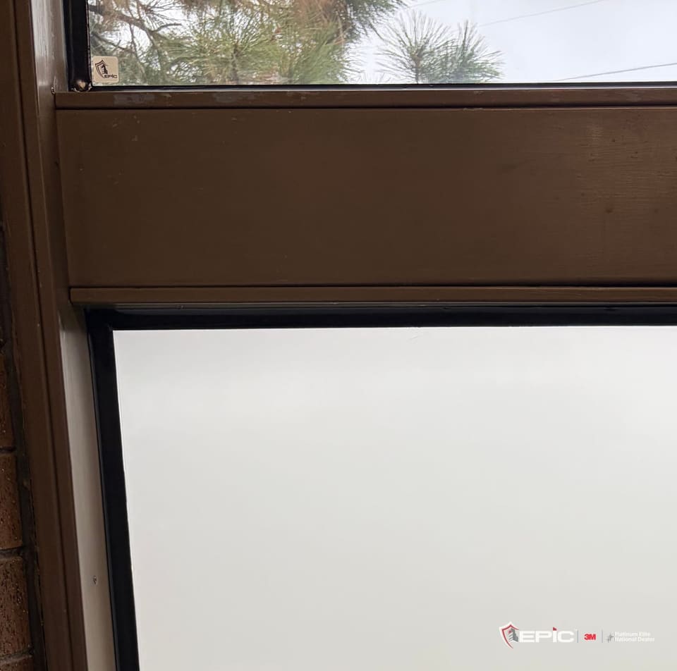 Close view of the frosted lower lite of a classroom window, an even white panel inside its dark frame