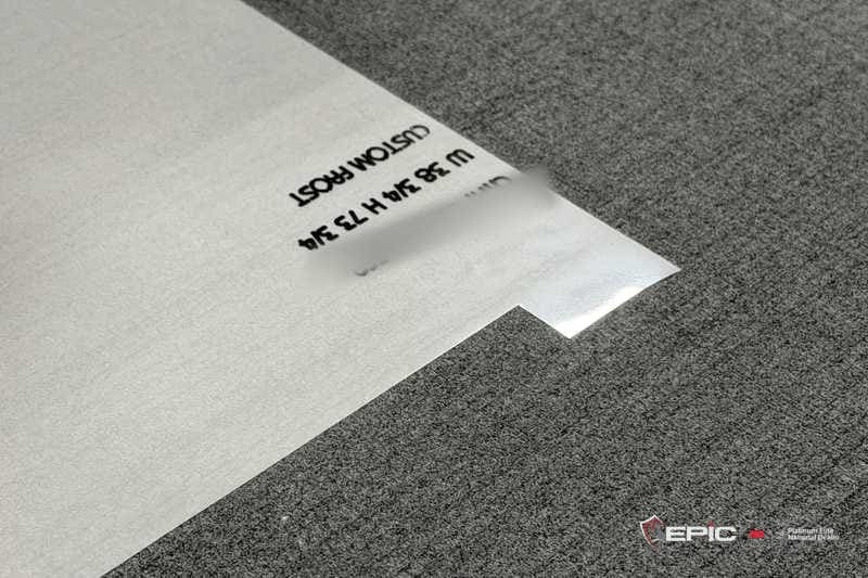 A sheet of frost film on a gray floor with its size and the words CUSTOM FROST printed on the liner
