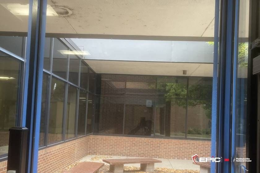 A tall entry lite taped blue on all four sides, stone benches and fall leaves in the courtyard beyond