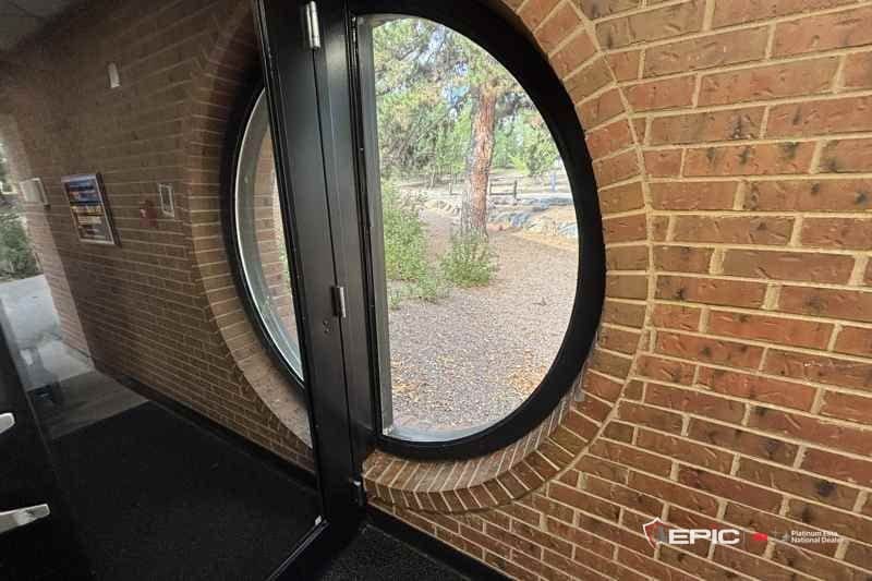 The round window beside the entry door with the 3M IPA bead run and the tape pulled, playground beyond