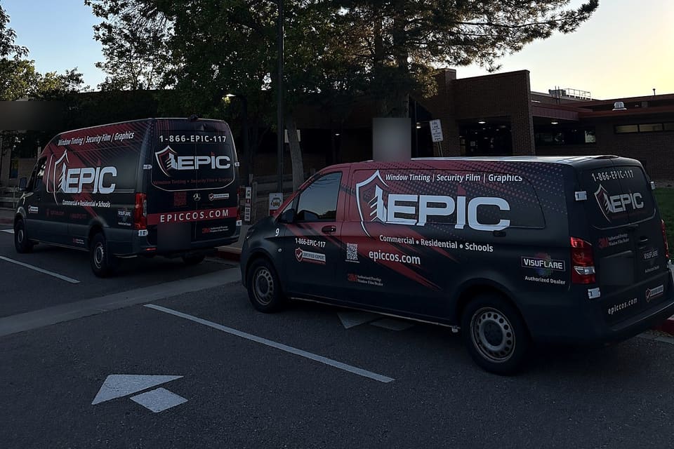 Two Epic vans parked at a school entrance at first light