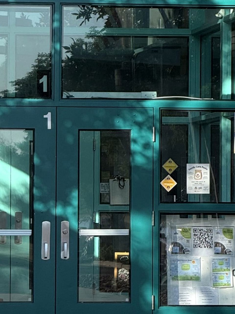 School entry with door number, security decals and a flyer in a reusable holder over the security film