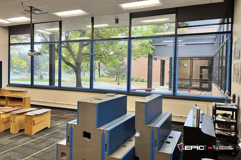 Music-room windows and transoms taped blue ahead of 3M S2400, choral risers and xylophones in the foreground