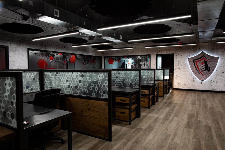 Open office with hexagon frosted panels on the workstation dividers and a lit shield on the wall