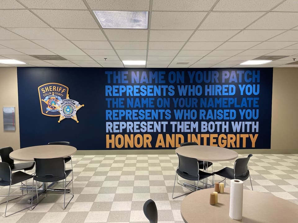 Sheriff’s office break room wall mural with the department seal and motto