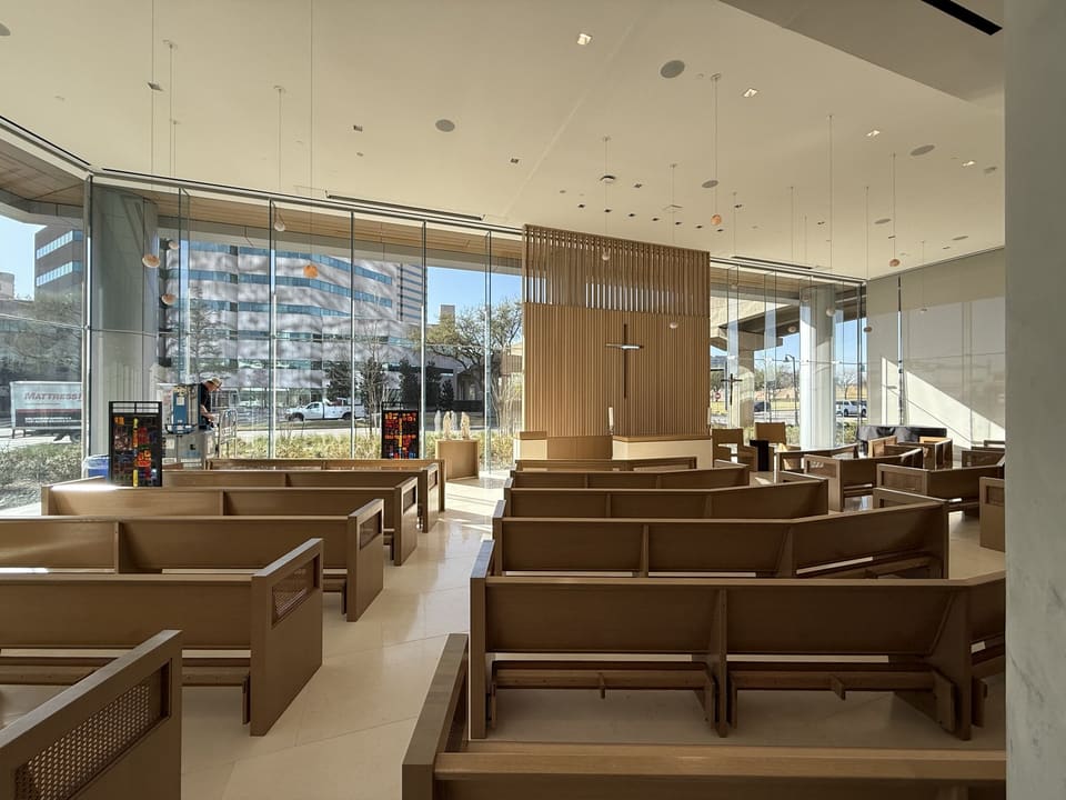 Chapel curtain wall mid-install: film on the left-hand panes, the right-hand panes still untreated