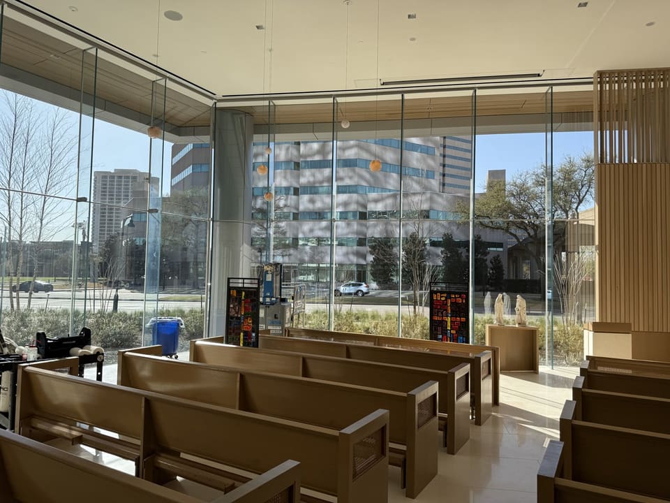 Chapel interior in Irving: rows of wooden pews facing a floor-to-ceiling glass curtain wall with 3M Prestige 60