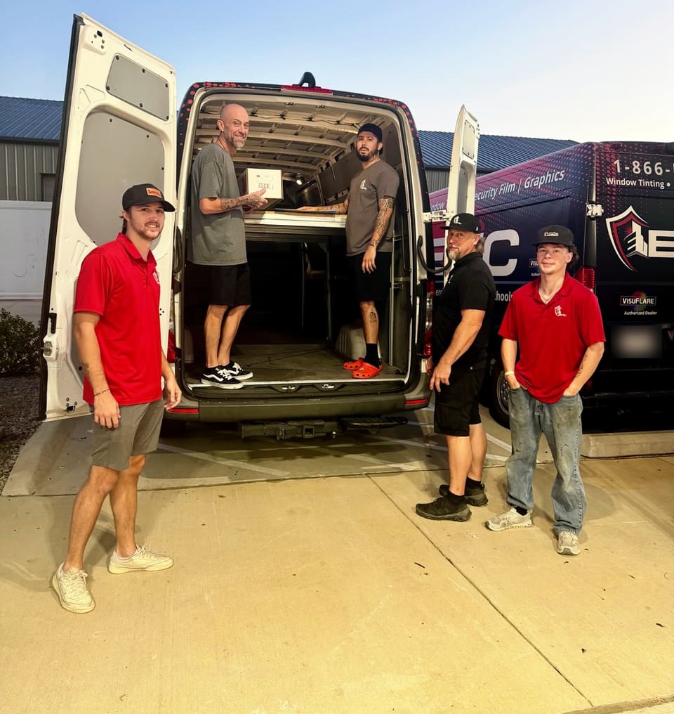 Five Epic crew members at the open rear doors of a van at the McKinney shop