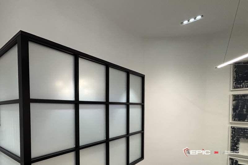 A black-framed office front with frosted glass, seen from the stair landing
