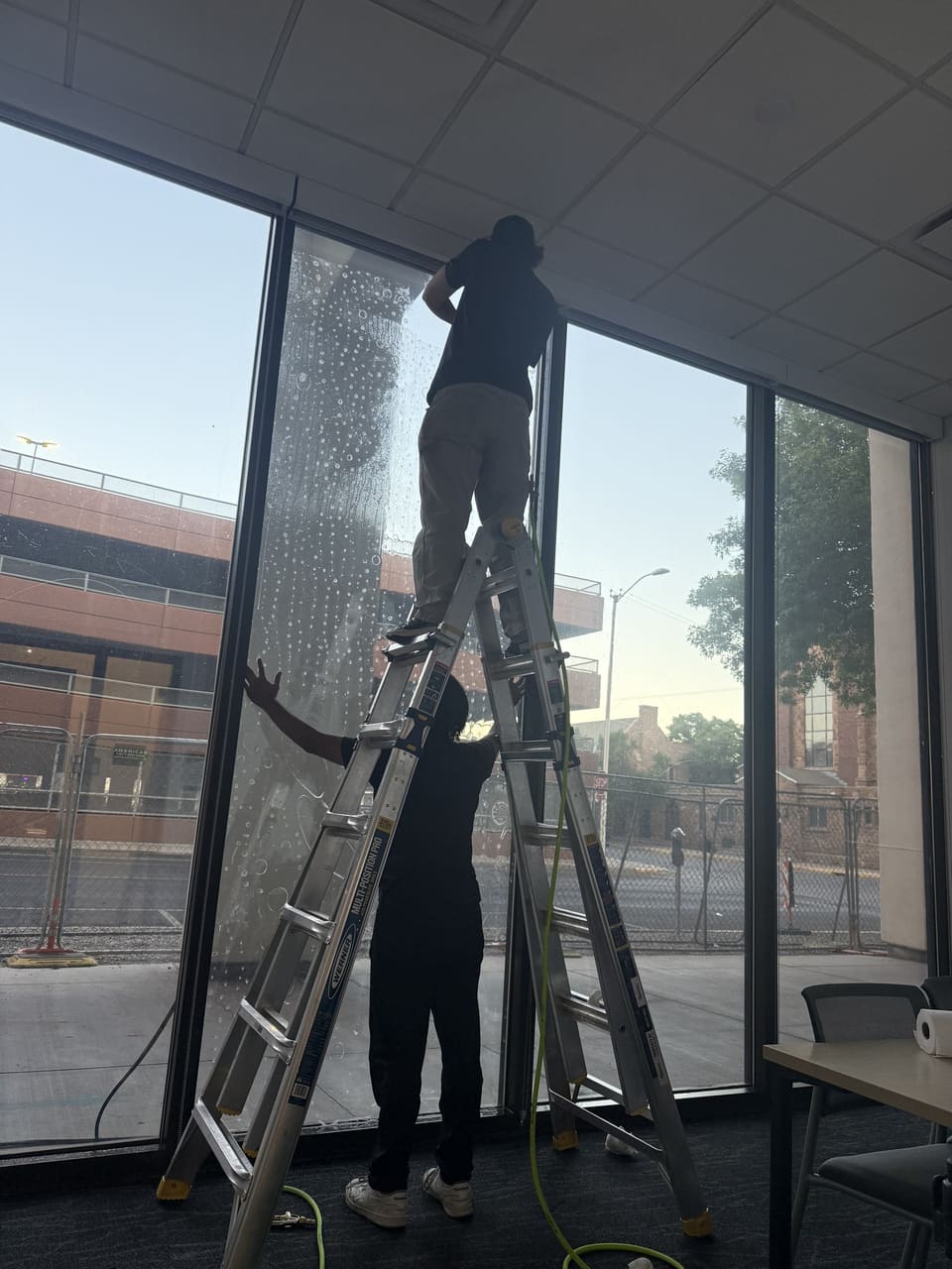 Epic Certified Installation Specialist installing 3M security film on tall street-level glass at a county government building in Albuquerque