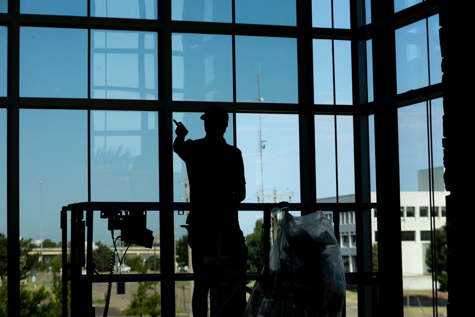 Epic installer silhouetted against the atrium glass during the film install at the Oklahoma Department of Wildlife Conservation