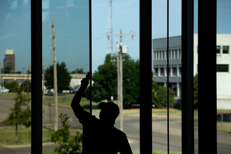 Epic installer silhouetted against the atrium glass during the film install at the Oklahoma Department of Wildlife Conservation