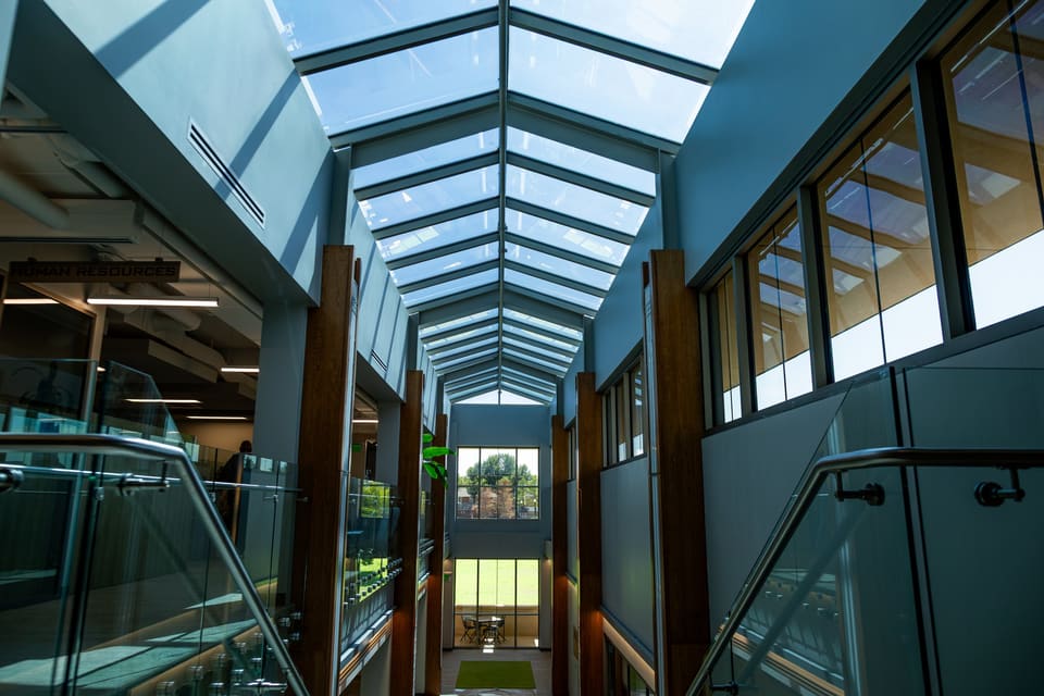 Atrium stair with a glass railing beneath a long skylight