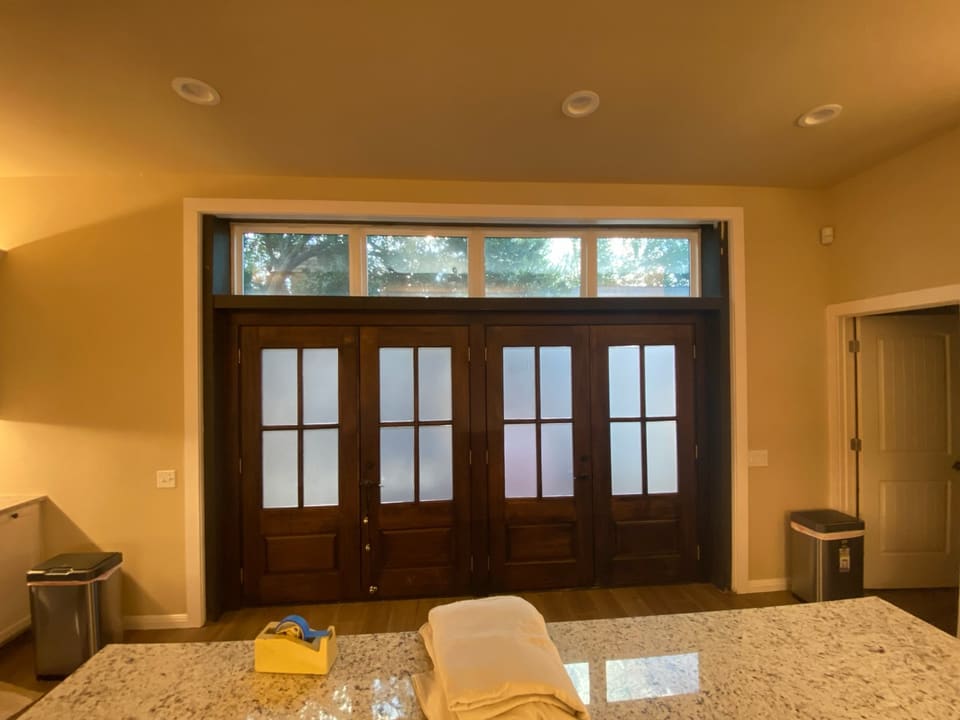View from a kitchen counter to frosted wood French doors under a clear transom