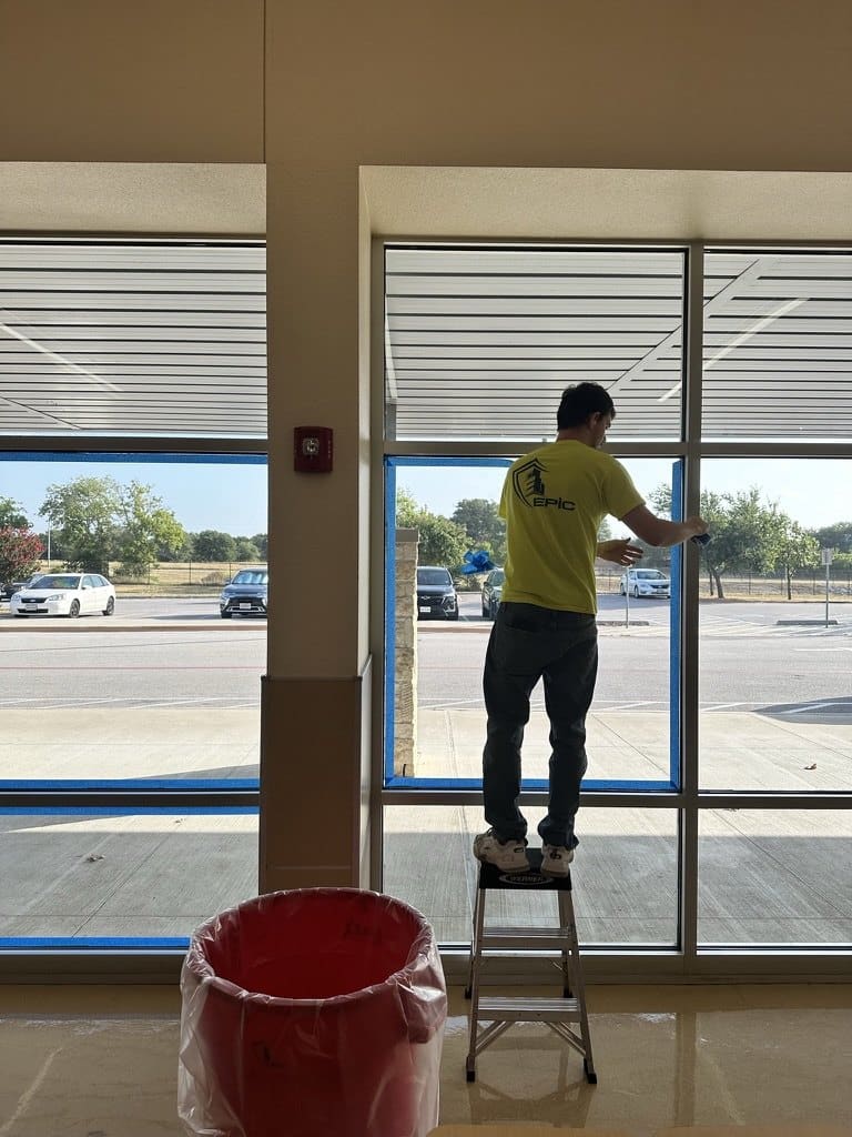 Certified Installation Specialist on a step ladder pulling the tape from the frame after the sealant is tooled